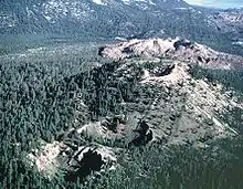 Dos cráteres in un área boscosa y un cráter en la cima de una colina grande. Un mogote masivo pero de colina plana está en el fondo.