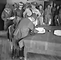 Baba firmando el documento de rendición en Labuán, Borneo británico, siendo observado por el mayor general australiano George Wootten y otras unidades australianas el 10 de septiembre de 1945.