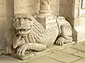 León esculpido como soporte de una columna.