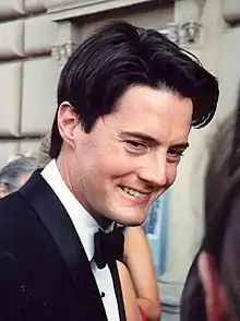 A man in his 30s, wearing a suit with a black bow tie.
