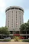 Ground-level view of a 17-story building with a tan stucco facade.