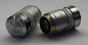 Dos objetivos de microscopio de inmersión de aceite Leica (izquierdo 100×, derecho 40×).