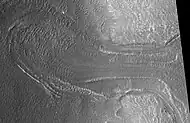 Probable glaciar visto por HiRISE bajo el programa HiWish . Los estudios de radar han encontrado que está compuesto de hielo casi completamente puro. Parece estar moviéndose desde el terreno alto (una mesa) a la derecha.