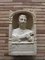 Estela conmemorativa de una mujer romana de 16 años, representada tocando un instrumento tipo pandura, fecha estimada del siglo II d.C. Desenterrada en 1956 en el sitio arqueológico Emerita Augusta en España. Conservada en el Museo Nacional de Arte Romano de Mérida, España