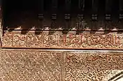 Inscripción con caligrafía árabe tallada en madera en la Madrasa de Sahrij en Fez, rodeada de otra decoración a base de arabescos (principios del siglo XIV)