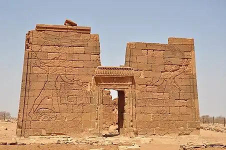 Pilons con reina Amanitore y rei Natakamani destrozando enemigos. La reina sostiene una espada, el rey un hacha