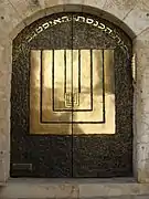 Inscripción hebrea y menorá en las puertas de la sinagoga.