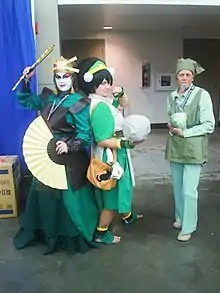 Tres personas disfrazadas haciendo cosplay de Avatar The Last Airbender: Suki, Toph y el vendedor de lechugas.