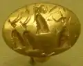 Anillo-sello de oro grabado con figuras femeninas.