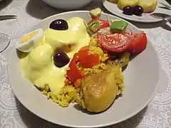 Arroz amarillo con pollo, acompañado de papa a la huancaína y ensalada de aguacate y tomate, en Perú