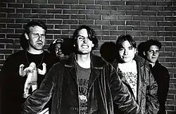 Miembros de Pavement parados frente a una pared de ladrillos posando en una foto en blanco y negro