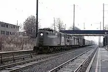 Dos locomotoras eléctricas arrastran vagones cerrados.