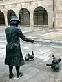 Mujer con gallinas en frente de las arcadas del mercado