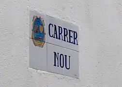 Placa de una calle donde se puede ver el antiguo escudo.