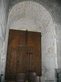 Puerta empotrada bajo una bóveda decrépita, que muestra el aparato de ladrillo utilizado.