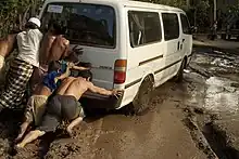 Personas empujan una van en una carretera inundada en Camboya
