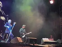 R.E.M. actuando en el escenario, con Michael Stipe cantando, Peter Buck tocando la guitarra y Scott McCaughey tocando los teclados