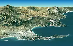 Ciudad del Cabo desde el espacio, mirando hacia el este sobre la península del Cabo y False Bay (detrás) con la isla Robben (frente izqda.), montaña de la Mesa (frente centro) y Cape Point (frente dcha.).