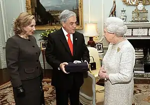 Presidente Piñera junto a la Reina Isabel II, entregándole una roca de la mina San José como obsequio.
