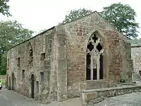 A low stone building with a large window, devoid of glas