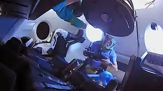 Miembros de la Expedición 58 ingresan al Dragon 2 por primera vez. Están usando equipo de protección para evitar respirar partículas que pueden haberse soltado durante el lanzamiento.