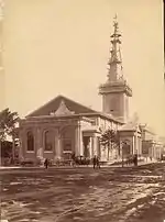 Una foto antigua mostrando la iglesia con un camino e terracería en primer plano y un andamio alrededor de la aguja.