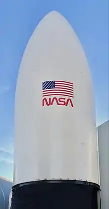 Photograph of a white nosecone with NASA logo and US flag