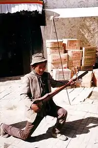 Músico callejero tibetano tocando un drumyin.