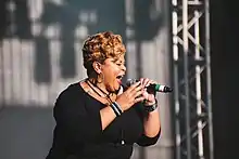 Tamela Mann sings into a microphone she is holding.
