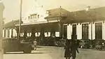 La estación en los años 1930. En frente de la estación se ven coches, peatones y un vendedor de frutas.