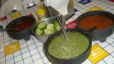 Acompañamiento de salsas y rodajas de limones en una taquería