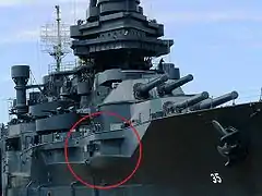 A permanently docked museum ship with a red circle on the photograph to highlight a gun protruding from an opening in the ship's port side.