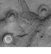 Cráteres con centros blancos en Mare Acidalium. Las dunas de arena son visibles en áreas bajas en la imagen. Algunas de las características pueden ser volcanes de lodo. Fotografía tomada por Mars Global Surveyor en el marco del Programa de focalización pública del MOC.