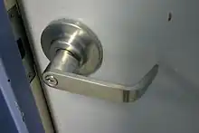 A silver-colored door handle on a white door