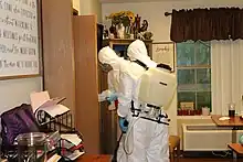 Two people in hazmat suits disinfecting surfaces at a nursing home