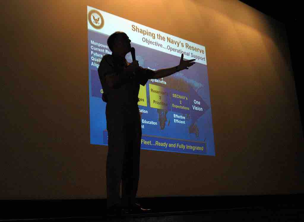 Vice Adm. John G. Cotton, is silhouetted during PowerPoint Presenation