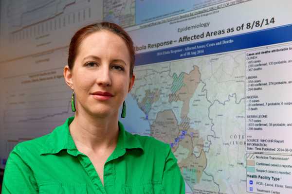 Photo: CDC Disease Detective Molly stands near the electronic information wall in the CDC’s Emergency Operations Center in Atlanta.