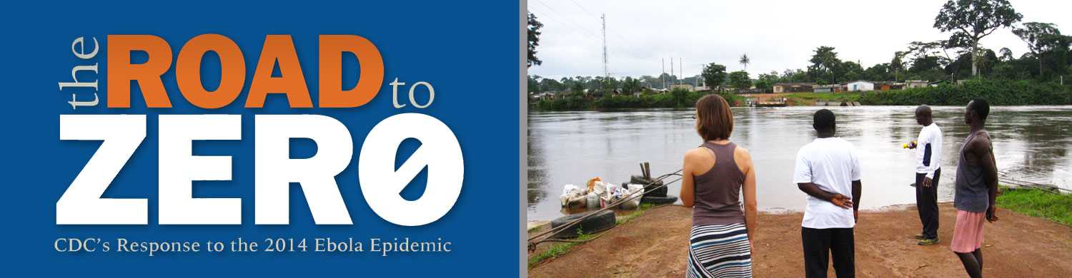 CDC responder Karlyn Beer (left) and local officials look across a river that acts as a border between Liberia and Cote d’Ivoire. The power lines show how electricity is generated in Cote d’Ivoire and carried across to Liberia.  