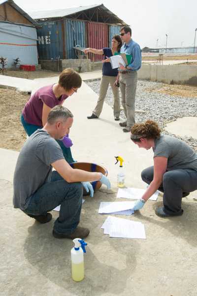 CDC staff spray a bleach solution on paperwork received from a rural health post at CDC’s lab in Bo, Sierra Leone.