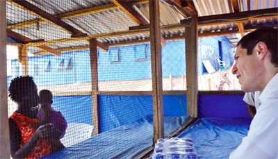 Dr. Tom Frieden speaks to a patient from the family visitor area at the Bong Ebola treatment unit in Liberia.