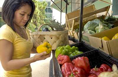 Woman standing in a farmer's market considering her purchase.