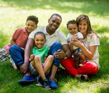 Photo of two parents and three children sitting outside