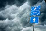 Photo of hurricane evacuation sign with storm in the background.