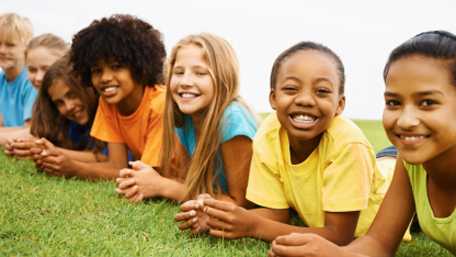 Photo of children lying on grass facing camera smiling