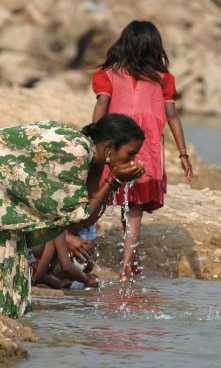 two Southeast Asian women washing their hands in a river