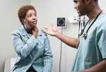 Doctor taking notes while talking to patient