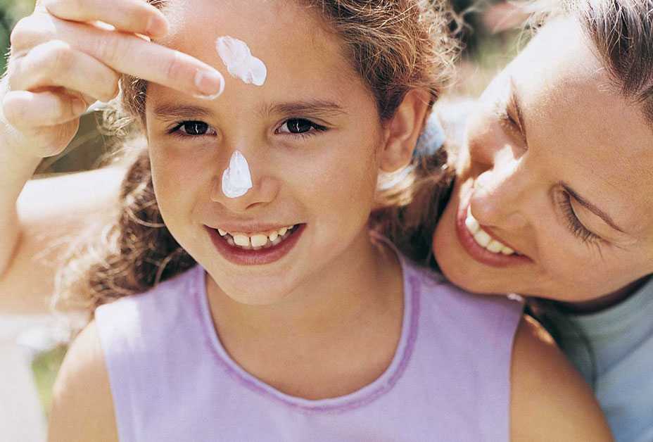 Mother applying sunscreen to daughter's face