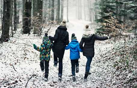 Mother and children walking down snowy trail