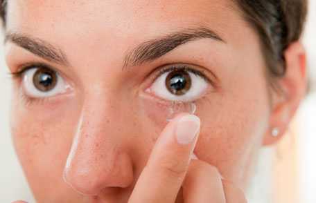 Woman inserting contact lens in eye