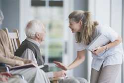 Senior man, rocking in chair and talking with nurse